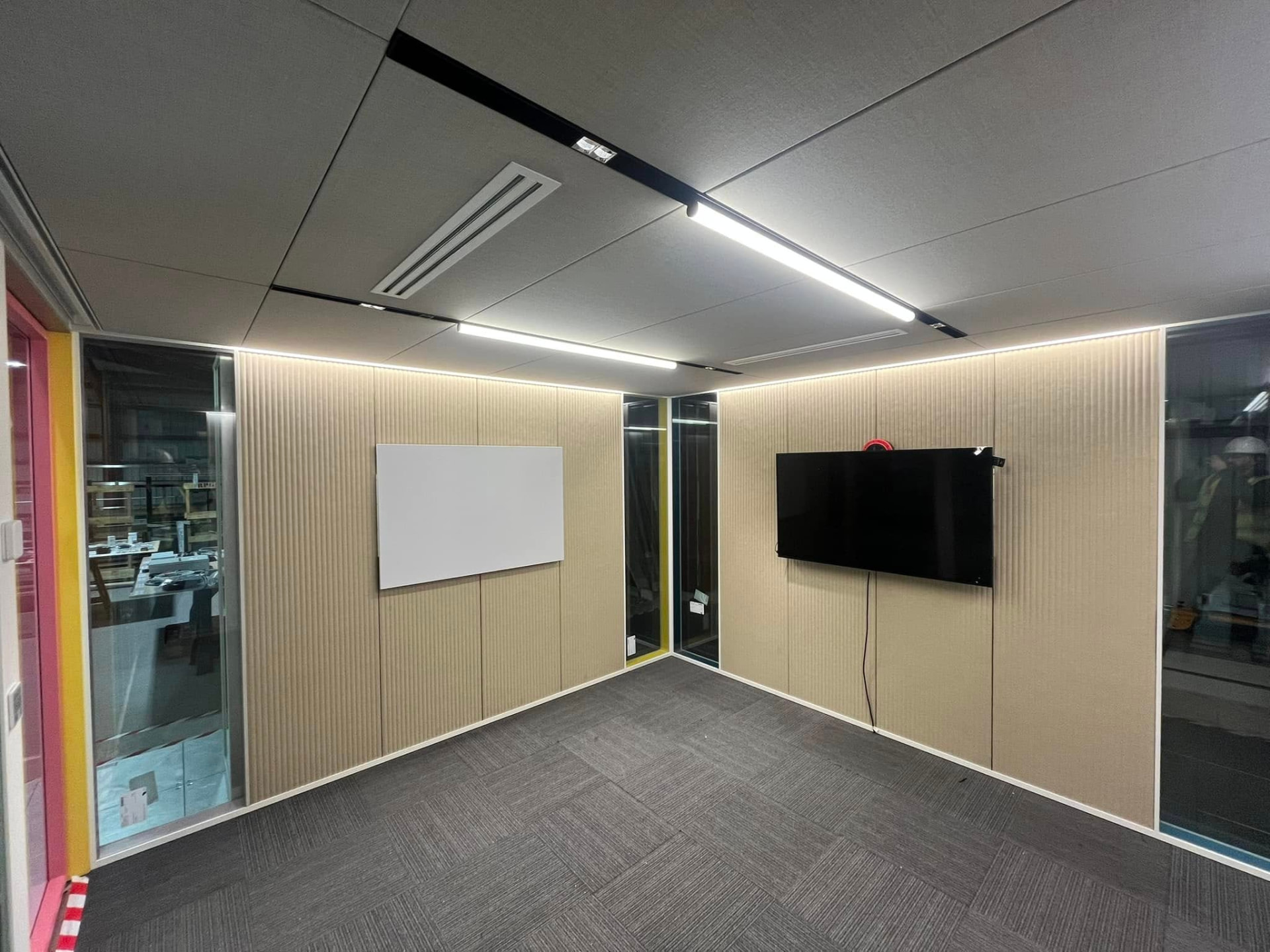 Modern office meeting room with feature ceiling lighting, ribbed wall panelling and glass partitions
