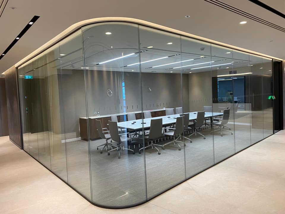 Curved glass partition enclosing a modern meeting room in a commercial office